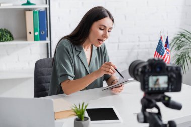 Tutor holding notebook near devices and digital camera in class 