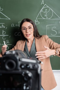 Matematik formüllerinin yanında konuşan öğretmen ve sınıfta bulanık dijital kamera. 