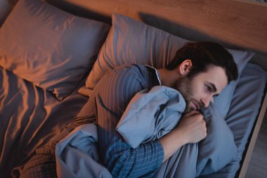 Geceleri uykusuzluk çeken pijamalı bir adam. 