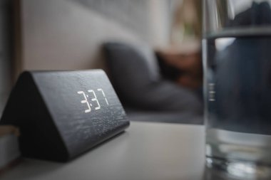 Yatak odasındaki su camının yanındaki elektronik alarm saatini kapat. 