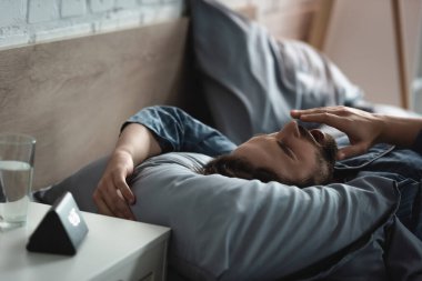 Young man yawning while lying on bed in morning 