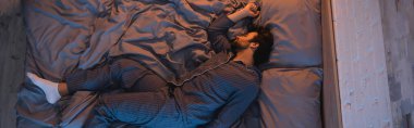 Top view of man in pajama sleeping in bedroom at night, banner 