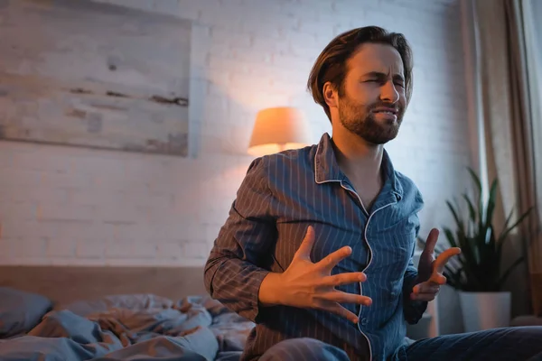 Tensed man in pajama sitting on bed at night