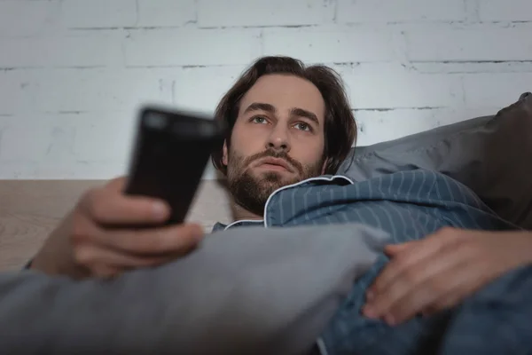 Young Man Holding Blurred Remote Controller Bed Night — Stok Foto