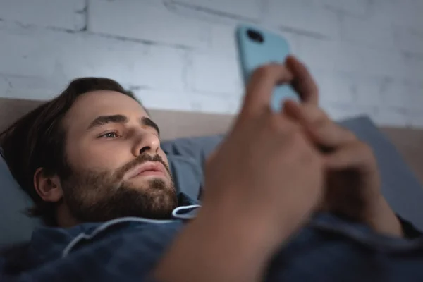 Homem Barbudo Pijama Usando Smartphone Desfocado Cama Noite — Fotografia de Stock