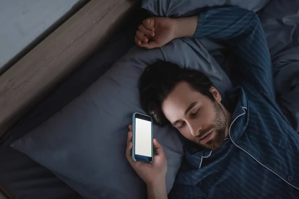 Visão Superior Jovem Segurando Smartphone Com Tela Branco Enquanto Dorme — Fotografia de Stock