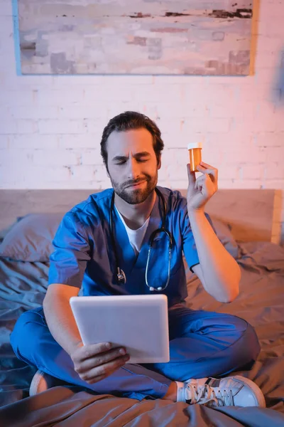 Confused Doctor Holding Pills Digital Tablet While Suffering Sleepwalking Bed — Zdjęcie stockowe