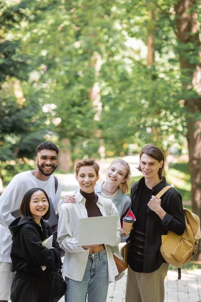 Multietniska Studenter Som Håller Bärbar Dator Och Ler Mot Kameran — Stockfoto