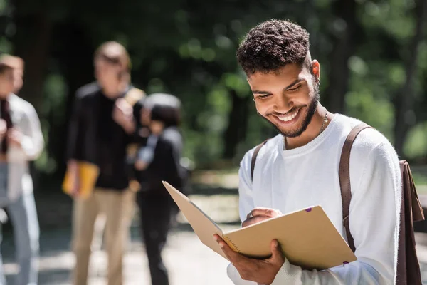 Smiling African American Student Backpack Writing Notebook Outdoors — Foto de Stock