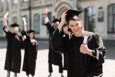 Gülümseyen bekar şapkası ve diploması açık havada. 