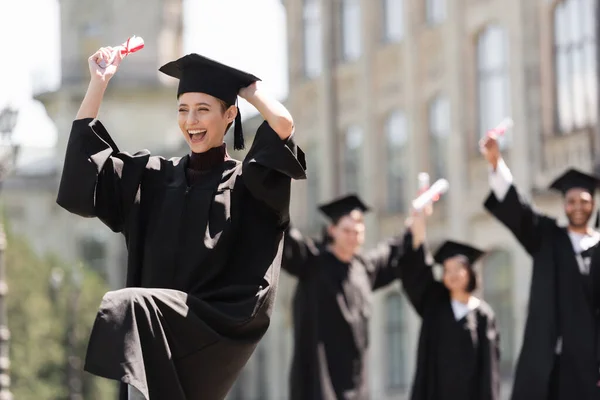 Cheerful Bachelor Cap Holding Diploma Blurred Multiethnic Friends Outdoors — 스톡 사진