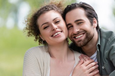 portrait of pleased woman and happy bearded man looking at camera clipart