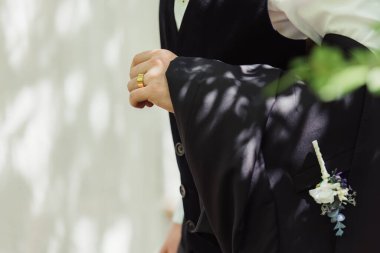 cropped view of groom in formal wear with golden wedding ring on finger