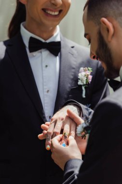 Sakallı eşcinsel adam mutlu damadın parmağına yüzük takıyor. 