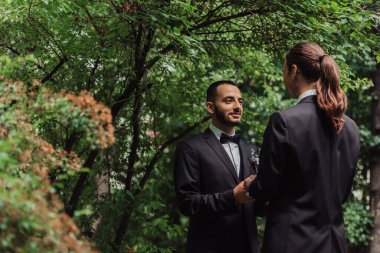 Resmi olarak evlenen mutlu eşcinsel çiftler birbirlerine bakıp parkta el ele tutuşurlar.