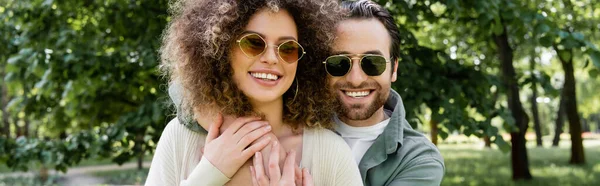 Happy Man Stylish Sunglasses Hugging Curly Girlfriend Park Banner — Fotografia de Stock