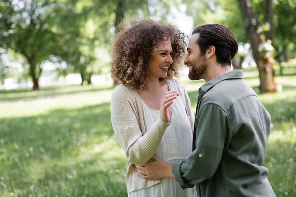 Fröhlicher Mann Umarmt Glückliche Und Lockige Frau Strickjacke Grünen Park — Stockfoto