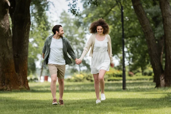 全身上下都是穿着夏装的笑容满面的夫妻 手牵手在公园里散步 — 图库照片