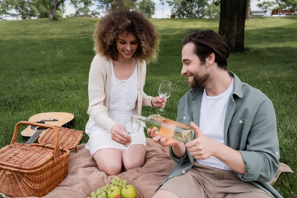 Hombre Alegre Verter Vino Vidrio Cerca Mujer Rizada Durante Picnic —  Fotos de Stock