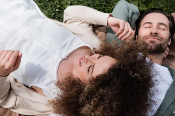 夏季公园野餐时 卷曲的女人躺在快乐的男朋友身上的高视角 — 图库照片