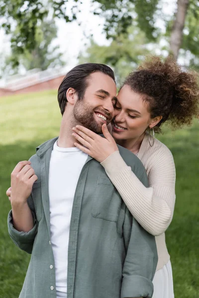 Pleased Curly Woman Hugging Happy Boyfriend Green Summer Park — ストック写真