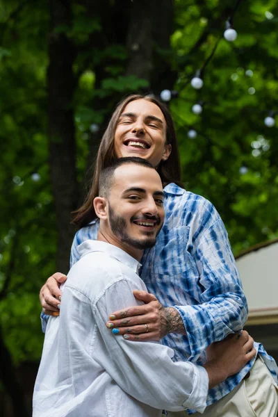Happy Married Gay Couple Smiling While Hugging Blurred Travel Van — ストック写真