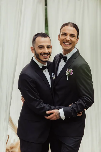 Happy Gay Couple Suits Boutonnieres Hugging Wedding Ceremony — Stock Photo, Image