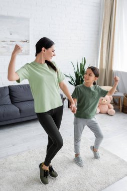 nanny and girl holding hands and smiling at each other while demonstrating strength