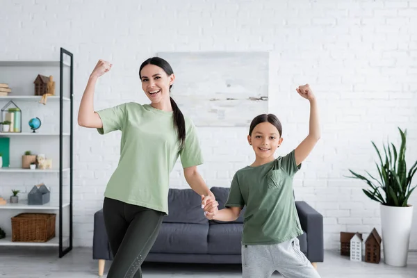 Cheerful Girl Babysitter Holding Hands Showing Muscles Living Room — Stockfoto