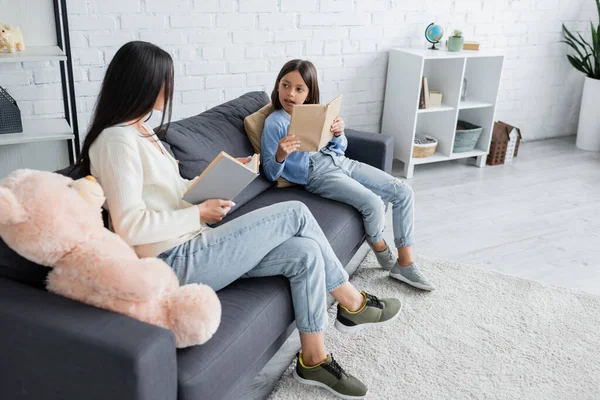 Kind Und Kindermädchen Sitzen Mit Büchern Auf Couch Wohnzimmer — Stockfoto