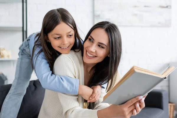 Menina Alegre Abraçando Babá Leitura Livro Casa — Fotografia de Stock