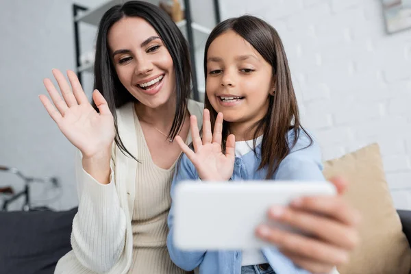 Fröhliche Babysitterin Und Mädchen Winken Bei Videoanruf Auf Verschwommenem Smartphone — Stockfoto