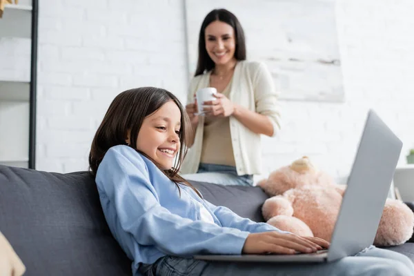 Animado Menina Jogos Laptop Perto Babá Com Xícara Chá Fundo — Fotografia de Stock