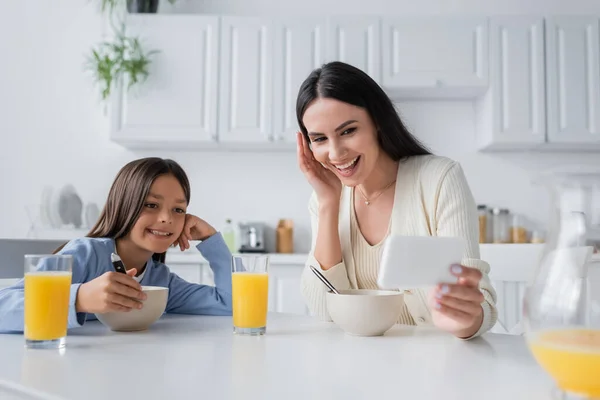 Babá Sorridente Mostrando Smartphone Enquanto Toma Café Manhã Com Menina — Fotografia de Stock