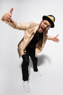 Doğu hip hop sanatçısı fötr şapkalı ve gözlüklü şarkı söylüyor.