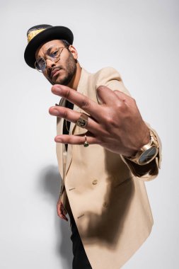 Doğu sakallı hip hop şarkıcısı fötr şapkalı ve gözlüklü.