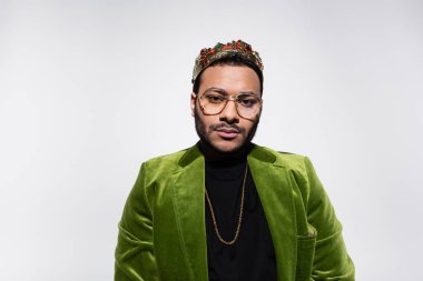 eastern hip hop performer in green velvet blazer and crown isolated on grey