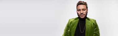 eastern hip hop performer in green velvet blazer and crown isolated on grey, banner