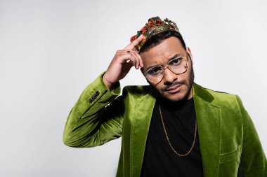 Yeşil kadife ceketli Hintli hip hop sanatçısı tacı gri renkte ayarlıyor.