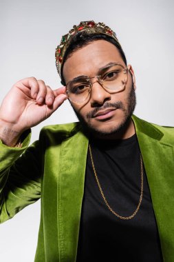 Doğu hip hop sanatçısı yeşil kadife ceketli ve tacı gri renkte ayarlıyor.