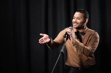 Hintli komedyen stand-up komedisi yapıyor ve mikrofonla espriler yapıyor.