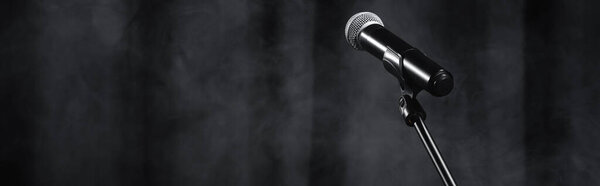 микрофон на стенде на черной сцене с занавесом и дымом, баннер