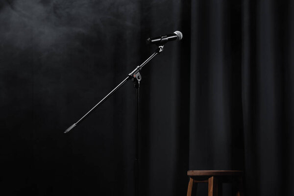 микрофон возле занавеса и деревянного стула на сцене с дымом