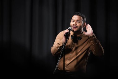 indian comedian listening during stand up comedy show on black  clipart