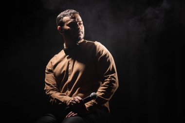 Siyah arka plana bakan gömlekli ve papyonlu Hintli komedyen.