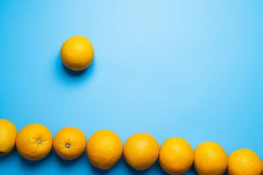 Düz uzanmış portakallarla mavi yüzeyde gölgeler