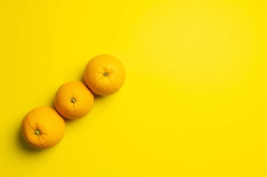 Top view of fresh oranges on yellow background 