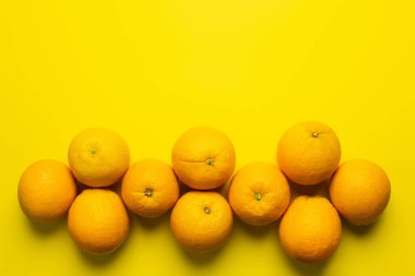Flat lay with organic oranges with shadow on yellow background 