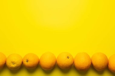 Flat lay with oranges in line on yellow background 