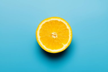 Top view of cut orange with shadow on blue background